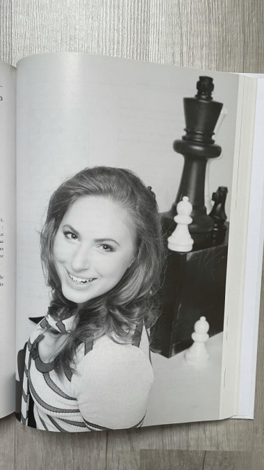 photo d'une page de livre avec une photo en noir et blanc d'une joueuse d'Ã©checs souriante.